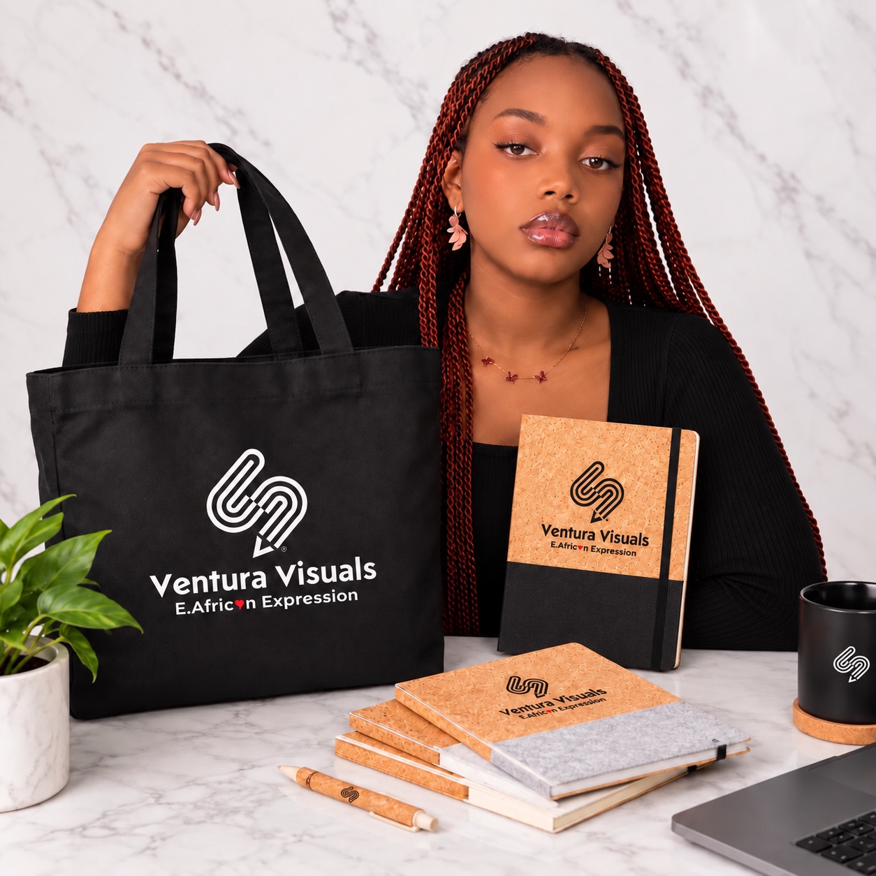 Model holding a Ventura Visuals tote and branded cork notebooks