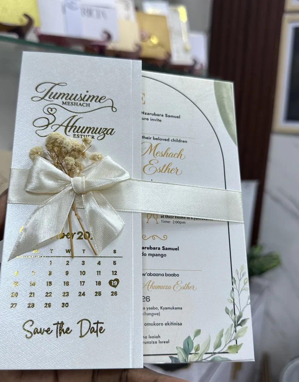 Ivory invitation with a gold monogram, ribbon and delicate dried flowers